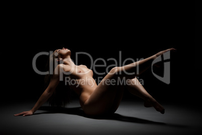 Naked woman posing at black studio background