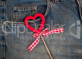 Red wooden heart on a background of blue worn jeans