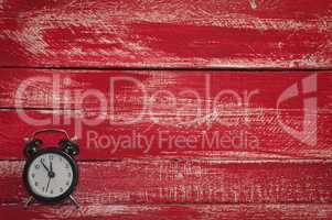 Old black clock on wooden red background