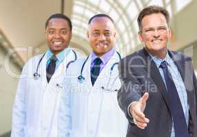 Mixed Race Doctors Behind Businessman Reaching for Hand Shake In