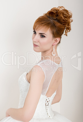 Beautiful young redhead bride wearing white wedding dress with professional make-up and hairstyle