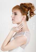 Beautiful young redhead bride wearing white wedding dress with professional make-up and hairstyle