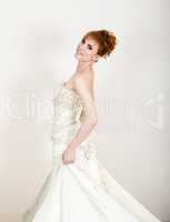 Beautiful young redhead bride wearing white wedding dress with professional make-up and hairstyle