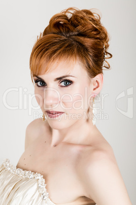 Beautiful young redhead bride wearing white wedding dress with professional make-up and hairstyle