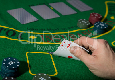 poker playing card on a green table background, man holding two aces