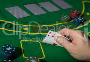 poker playing card on a green table background, man holding two aces