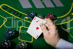 poker playing card on a green table background, man holding two aces