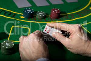 poker playing card on a green table background, man holding two aces