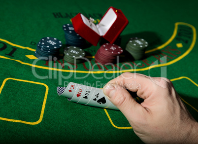 casino chips and a precious ring on green poker table background, man holding losing combination of cards