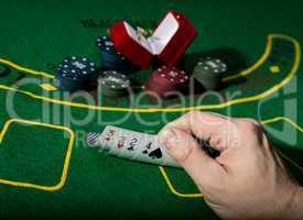 casino chips and a precious ring on green poker table background, man holding losing combination of cards