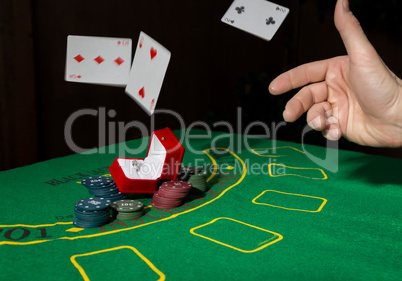 casino chips and a precious ring on green poker table background, man throws cards with losing combination.