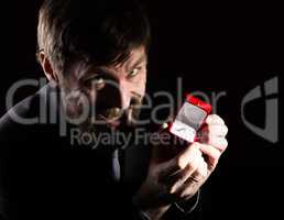 bearded man in business suit gives a ring in the red box and expresses different emotions on dark background