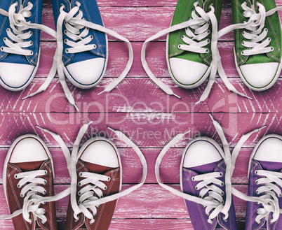 Youth colored sneakers on old pink wooden surface, top view