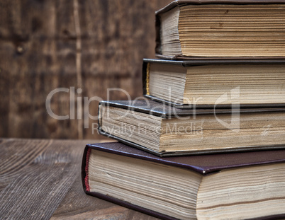 stack of old books on a brown wooden background