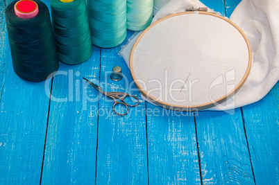Some turquoise thread with the fabric in the wooden embroidery f