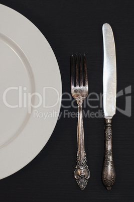 Half empty white plates, vintage knife and fork on  table