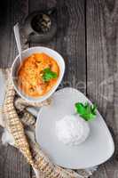 Chicken curry and rice served on a wooden surface.