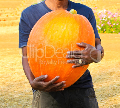 A man holding the big pumpkin.