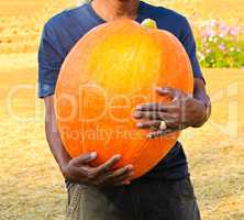 A man holding the big pumpkin.