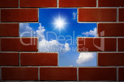 Brick wall and blue sky with clouds and sun.