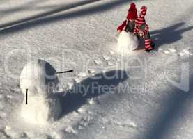 Small wooden doll in the scene of building a snowman