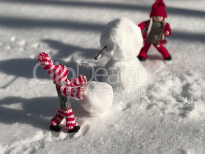 Small toys in the stage of building a snowman