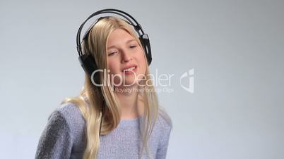 Emotional young blonde in headphones over white