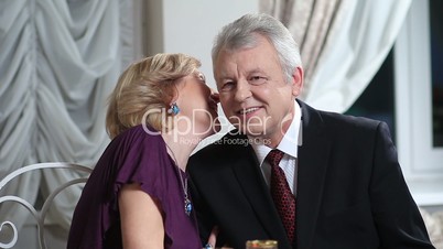 Smiling elderly woman whispering to husband
