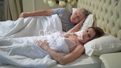 Senior woman in bed stretching and waking up