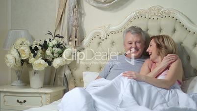 Excited senior couple laughing together in bed