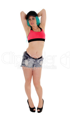 Woman in shorts with hands on head.
