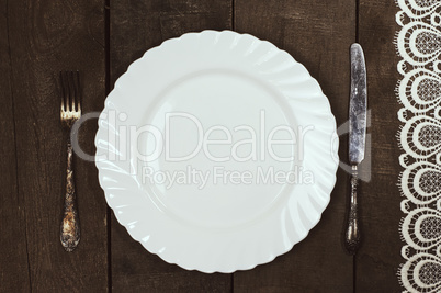 white plate with cutlery on a wooden surface