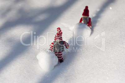 Two toy man with snow balls rolled snow-covered mountains