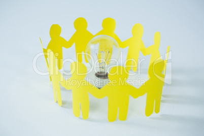 Circle of yellow paper cut-out figures and light bulb