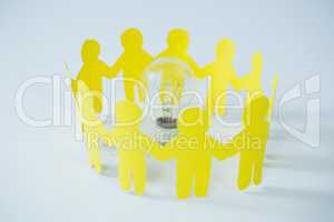 Circle of yellow paper cut-out figures and light bulb