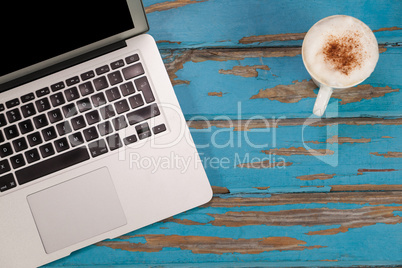 Coffee mug and laptop on wooden plank