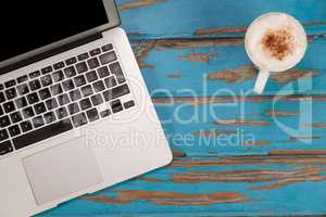 Coffee mug and laptop on wooden plank