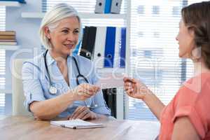 Doctor giving a prescription to her patient in medical office