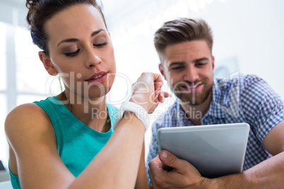 Man using digital tablet while colleague checking time