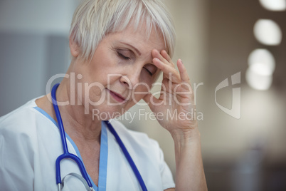 Tensed female nurse sitting in corridor