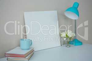 Picture frame, coffee cup with table lamp and flower vase