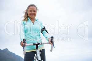 Portrait of happy woman standing with bicycle on beach