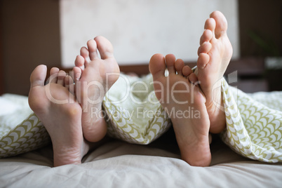 Couple showing their feet while lying on a bed