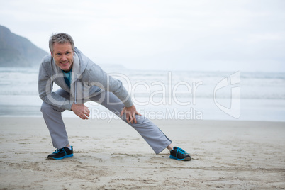 Man performing stretching exercise on beach