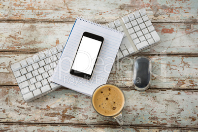 Cup of coffee with keyboard, mobile phone and mouse