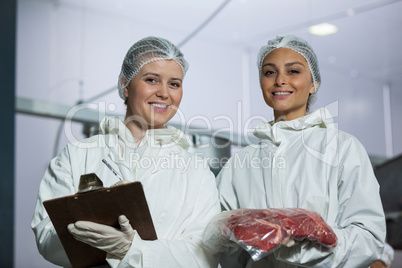 Female butchers maintaining records on clipboard