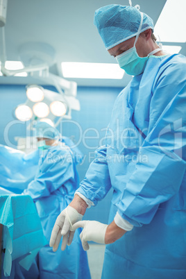 Male surgeon wearing surgical gloves in operation theater
