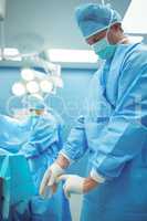 Male surgeon wearing surgical gloves in operation theater