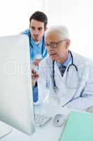 Surgeon and doctor discussing over personal computer