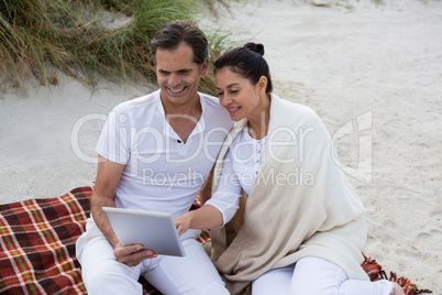 Happy couple using digital tablet on beach